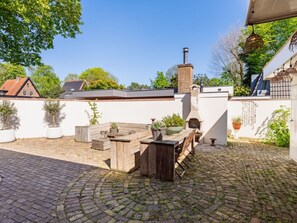 A patio with a brick floor, a wooden table, and a brick chimney. - Villa in Bergen With Swimming Pool (Bergen)