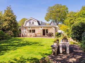 A house with a covered patio, a lawn, and a garden. - Villa in Bergen With Swimming Pool (Bergen)