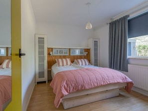 A bedroom with a bed, a window with curtains, a door, and a light fixture. - Holiday Home With 3 Bedrooms (Burgh-Haamstede)