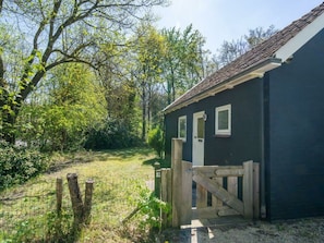A small building with a dark exterior, a wooden gate, and a fenced yard. - Holiday Home With 3 Bedrooms (Burgh-Haamstede)