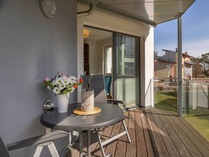 Ein Balkon mit Tisch, Stuhl, Blumenvase und Flasche.