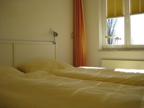 A bedroom with a single bed, a window with blinds, and a curtain. - 4 in Villa Seegatt (Norderney)