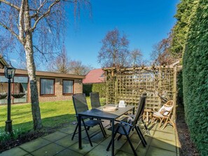 A patio with a table and chairs, a wooden fence, and a house in the background. - Holiday Home in Renesse With Swimming Pool (Renesse)