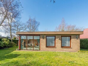 A modern house with a glass door entrance, brick walls, and a well-maintained lawn. - Holiday Home in Renesse With Swimming Pool (Renesse)