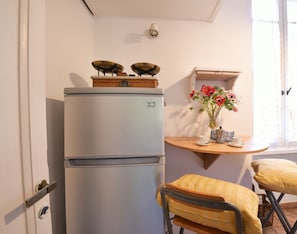 Eine kleine Küche mit einem Kühlschrank im Vintage-Stil, einer Holzwand mit Blumen und einem Tisch mit Stühlen.