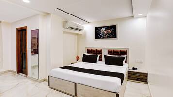 Una habitación de hotel moderna con una cama grande, una mesita de noche, un aire acondicionado instalado en la pared y un cuadro sobre la cama.