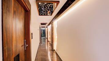Un pasillo con puerta de madera, suelo de mármol y un panel decorativo en la pared.