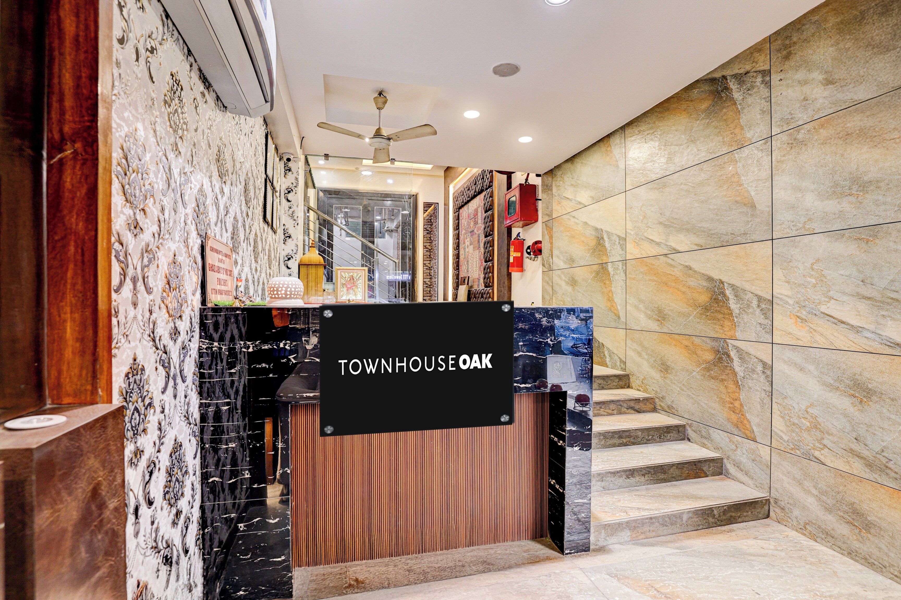 A hotel entrance with a sign reading 'TOWNHOUSE OAK,' a staircase, and a ceiling fan.