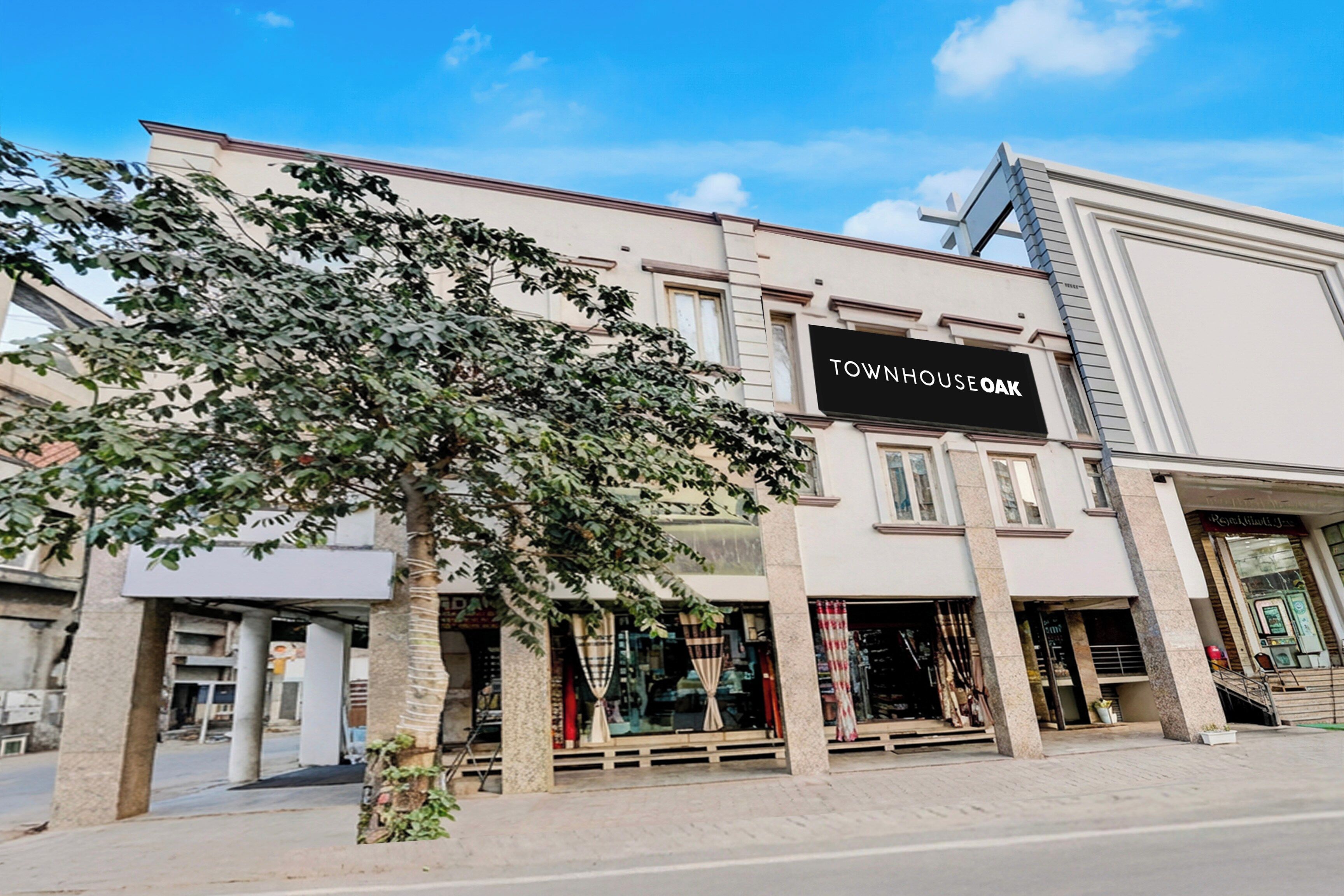 A building with a sign reading 'TOWNHOUSE OAK' and storefronts with glass fronts.