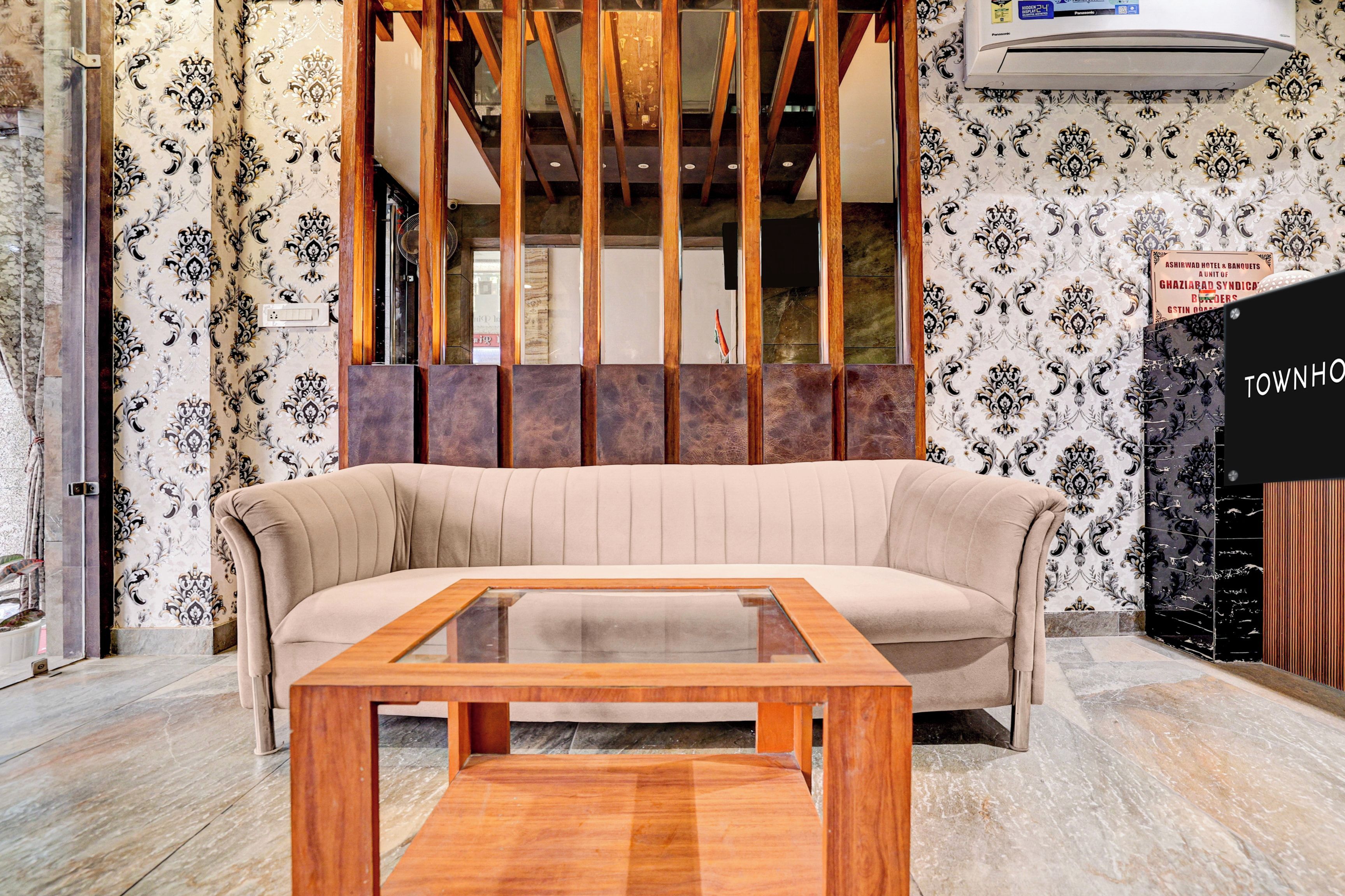 Una sala moderna con un sofá color beige, una mesa de centro de madera y papel tapiz estampado.