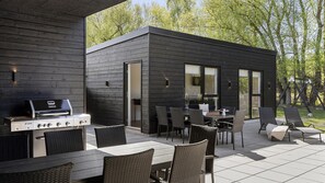 A modern outdoor patio with a grill, dining area, and lounge chairs. - VillaVilla 1011 - Fjellerup, Østjylland (Glesborg)