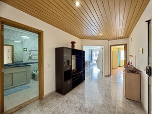 Un couloir avec un plafond en bois, une salle de bain avec une paroi en verre et un coin repas offrant une vue agréable.
