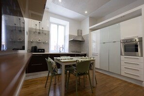 Cocina moderna con comedor, que incluye estufa a gas, horno y armarios blancos.