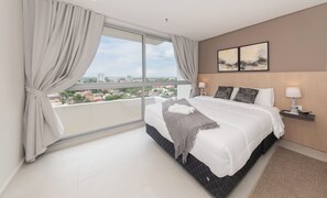 Ein modernes Hotelzimmer mit einem großen Bett, Blick auf die Stadt und minimalistischer Einrichtung.