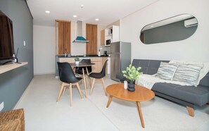 A modern living space with a dining area, sofa, and kitchen. - Mburucuya 1BR | Rooftop Pool, Gym & Parking (Asunción)