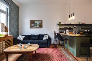 A modern living room with a dark sofa, a wooden coffee table, and a red patterned rug. - Secesyjne 80m Serce Jezyc (Poznań)
