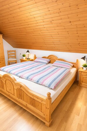 Ein Bett mit Holzrahmen und gestreifter Bettwäsche in einem Zimmer mit Holzwänden und -decke.