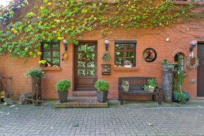 A brick building with a front door, two windows, and a bench.