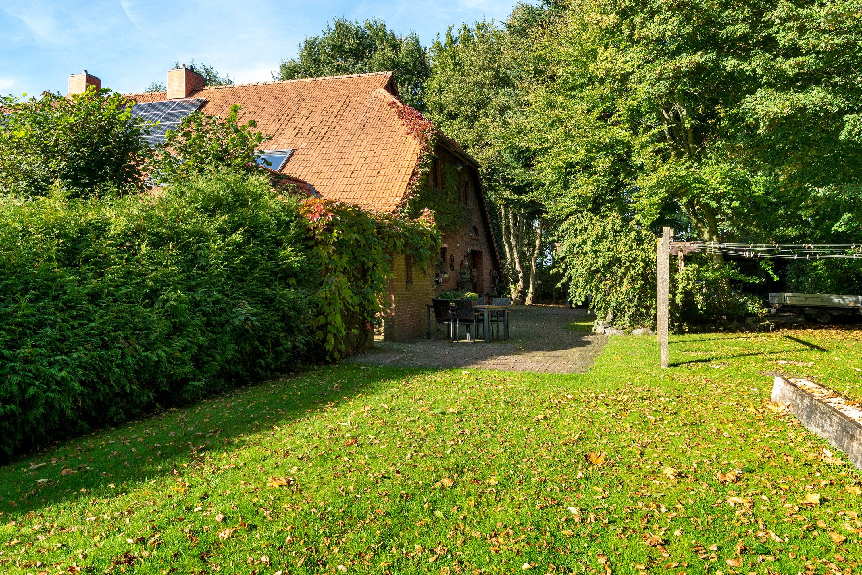 Ein rustikales Haus mit Ziegeldach, umgeben von üppiger Vegetation und einer gepflasterten Terrasse.