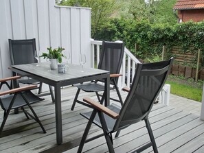 A deck with a table and chairs, surrounded by a white fence and greenery. - Captain's House Thule - Sea Buckthorn (Langeoog)