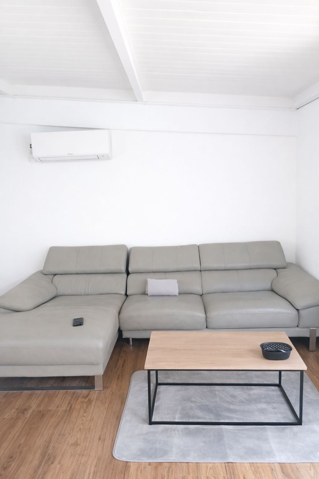 Een moderne woonkamer met een grijze modulaire bank, een houten salontafel en een grijs vloerkleed.