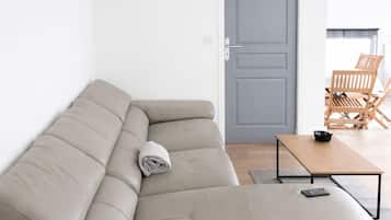 Un salon moderne avec un canapé d’angle beige, une table basse en bois et une porte grise.