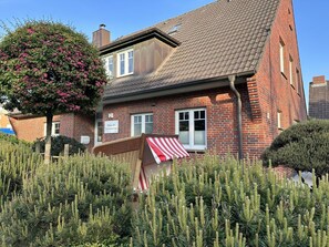 A brick house with a sloped roof, a front porch with a striped awning, and a sign indicating it is a private residence. - at the South Grove 3 (Sylt)