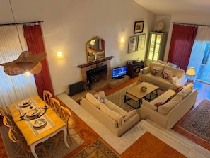 A living room with a fireplace, sofa set, dining table, and a television.