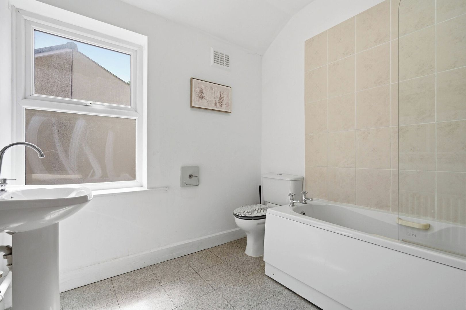A bathroom with a window, a sink, a toilet, and a bathtub.
