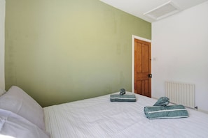 A bedroom with a bed, a radiator, a door, and a small statue on the bed. - Beautiful 2 Bed House with Parking in Birmingham (West Midlands)