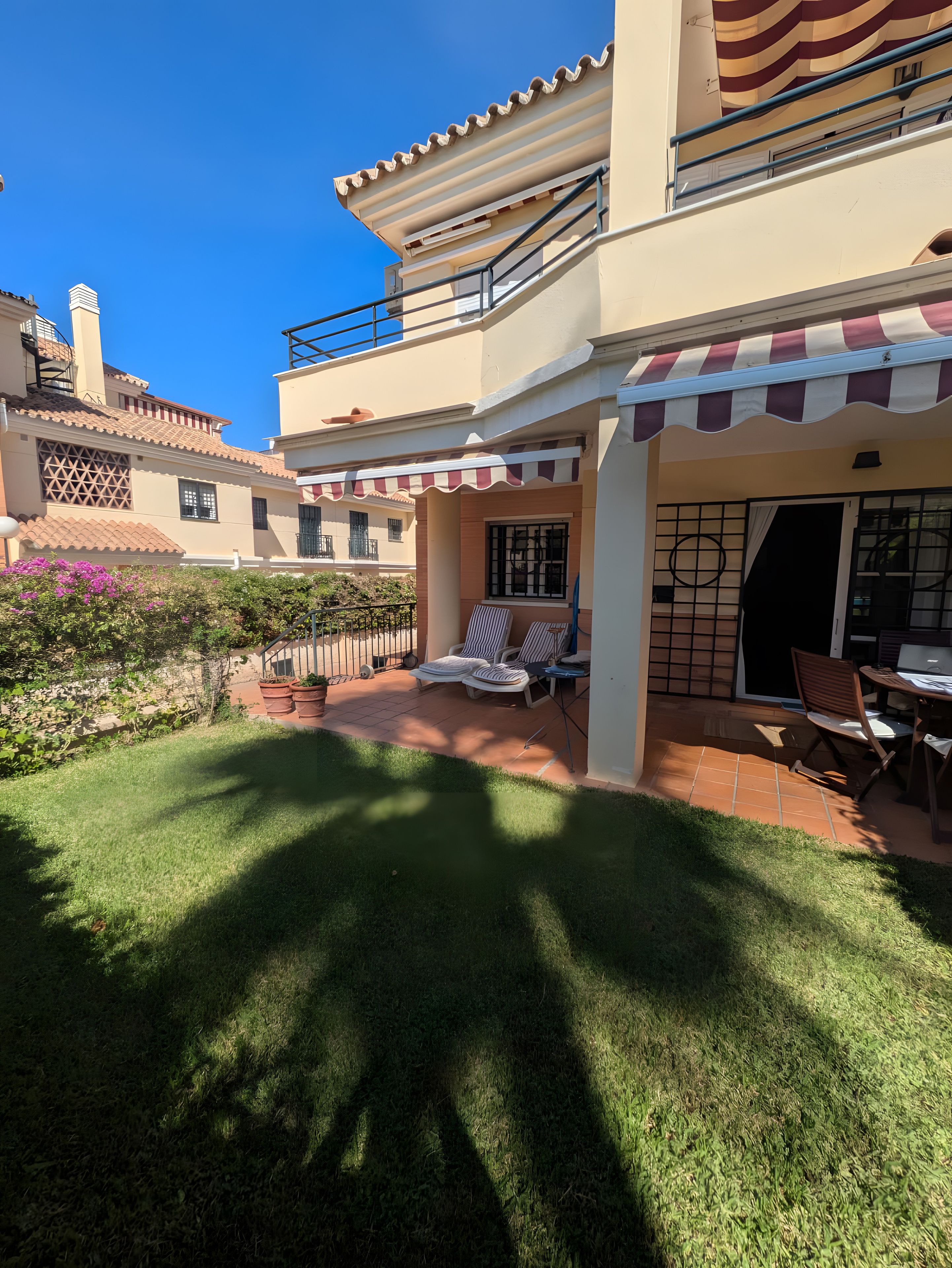 Ein Wohnhaus mit Terrasse, Sitzgelegenheit im Freien und Blick auf benachbarte Gebäude.