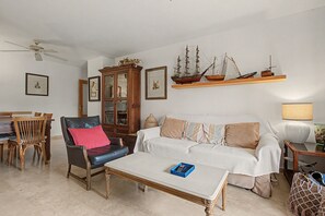 A living room with a sofa, armchairs, a coffee table, a cabinet, and a ceiling fan. - Apartment 'Baviera Golf Resort' with Shared Pool, Private Terrace and Wi-Fi (Caleta de Vélez)