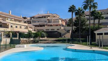 Una piscina rodeada de edificios con balcones y palmeras.