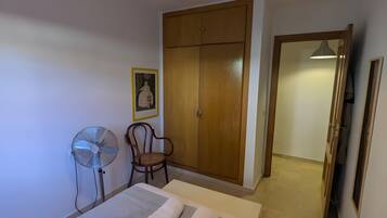 Ein Hotelzimmer mit einem Bett, einem Sessel, einem Kleiderschrank und einem Ventilator.