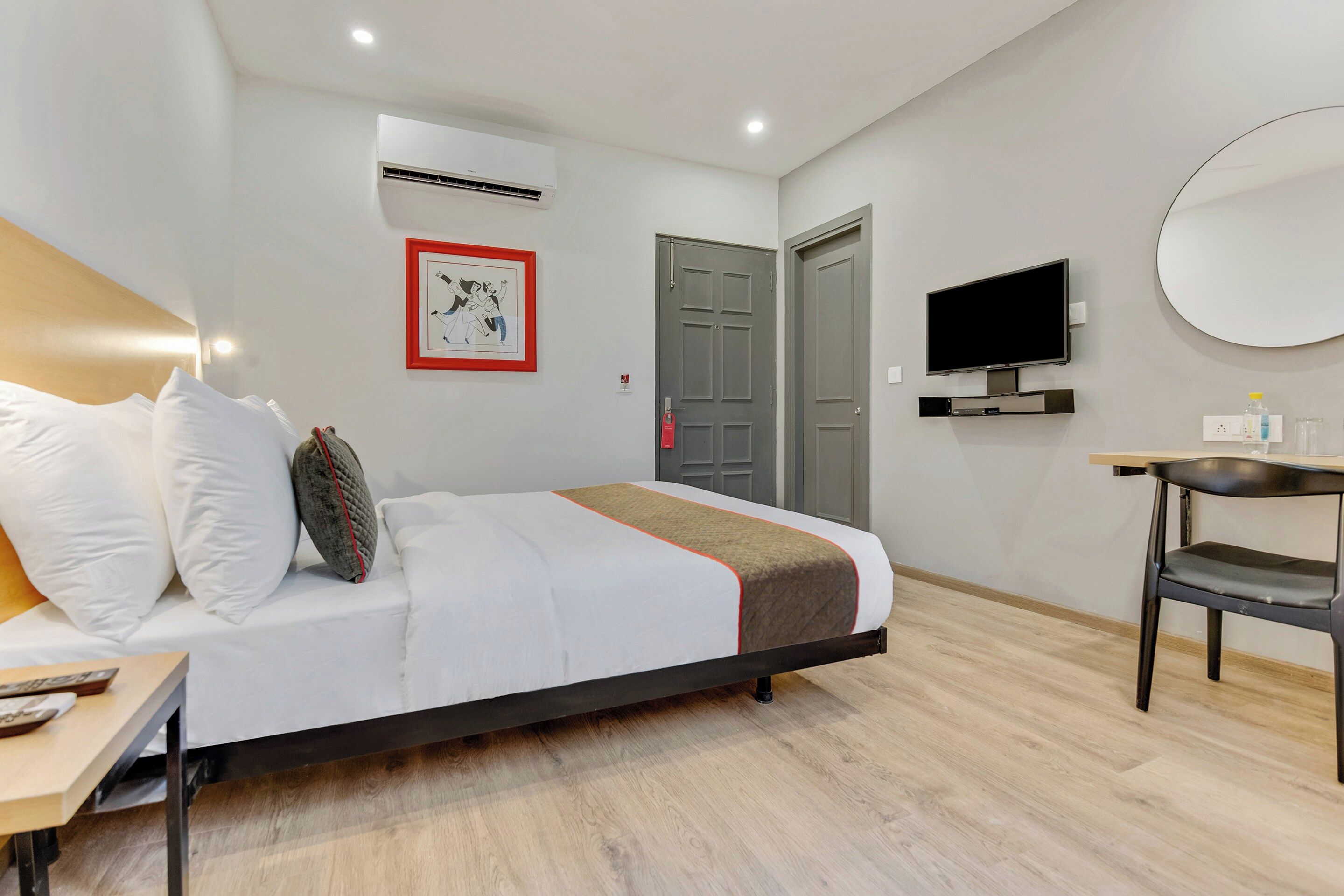 Una habitación de hotel con una cama, un escritorio, un televisor y una puerta.