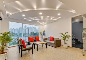Una sala moderna con un sofá, sillones, una mesa de centro y plantas en macetas.