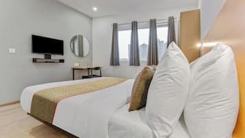 Habitació d'hotel amb llit, televisió, mirall, finestra amb cortines i vista a la ciutat.