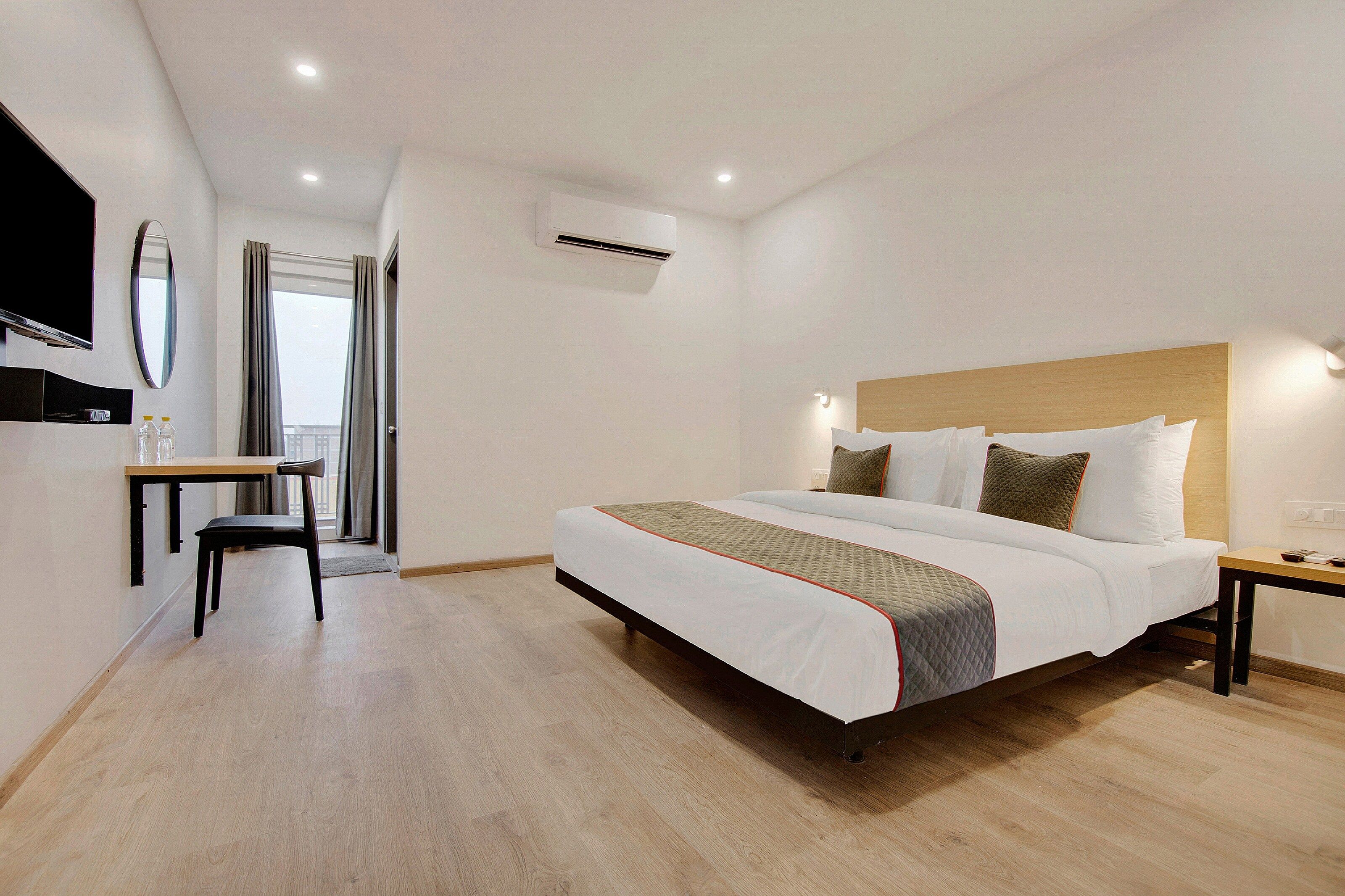 A hotel room with a bed, bedside table, and a desk with a chair.