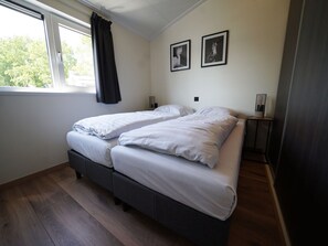 A bedroom with two beds, a window with curtains, and two framed pictures on the wall. - Holiday Home in Kampen With Swimming Pool (Kampen)