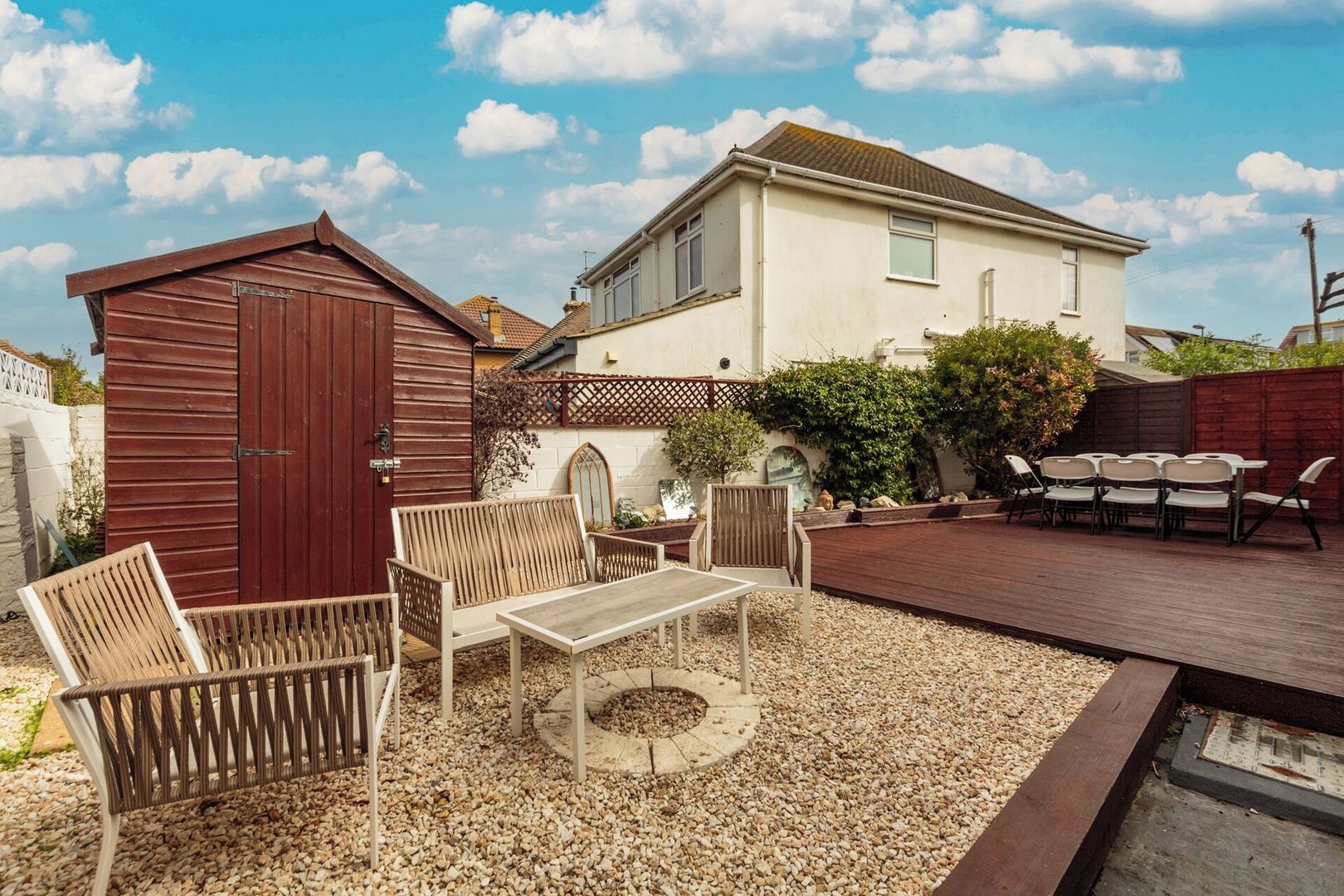 A patio area with outdoor furniture, a wooden deck, and a small shed.