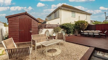 A patio area with outdoor furniture, a wooden deck, and a small shed.
