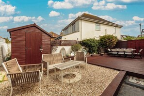 A patio area with outdoor furniture, a wooden deck, and a small shed. - Lancing 3BR Home | Parking for 3 Cars (West Sussex)