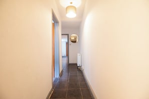 A narrow hallway with a ceiling light fixture and a radiator on the wall. - Cosy 1-Bed Garden Flat by Brighton Station (Brighton and Hove)