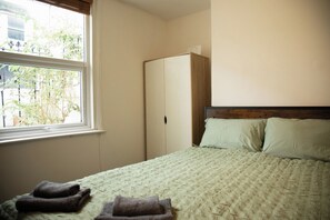 A bedroom with a bed, a wardrobe, and a window. - Cosy 1-Bed Garden Flat by Brighton Station (Brighton and Hove)