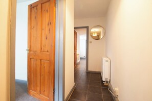 Um corredor com porta de madeira, radiador e espelho na parede.