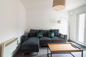 Een moderne woonkamer met een hoekbank, een houten salontafel en een vloerlamp.
