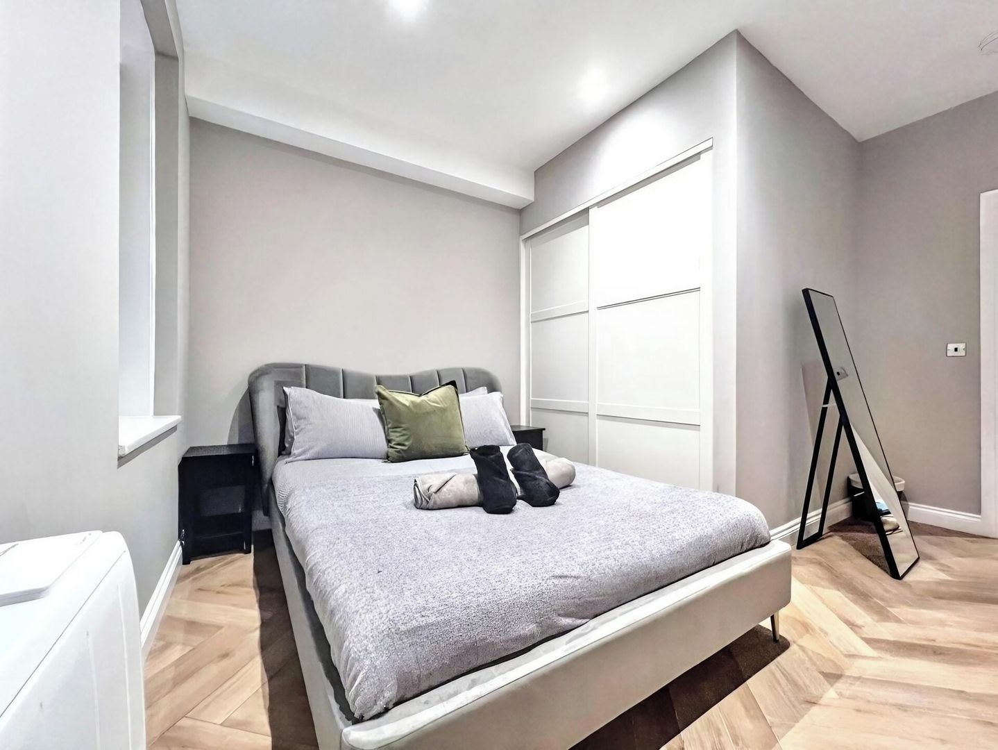 Une chambre à coucher comprenant un lit, des tables de chevet, une armoire et un miroir.