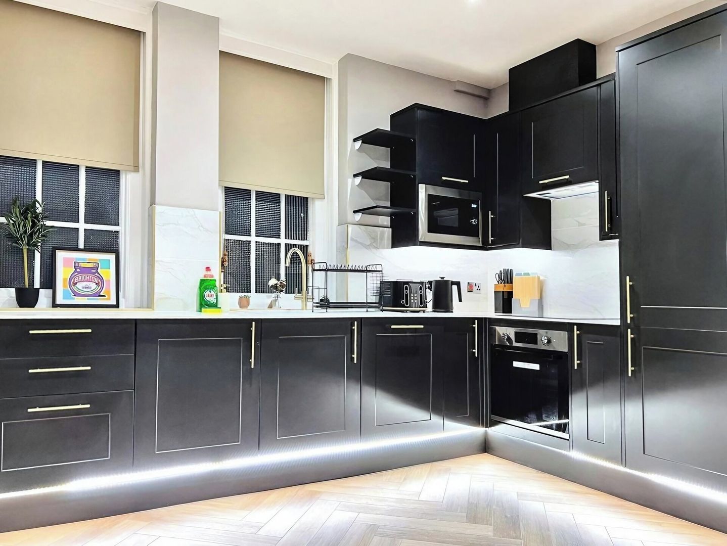 A modern kitchen with dark cabinetry, a microwave, and a coffee machine.