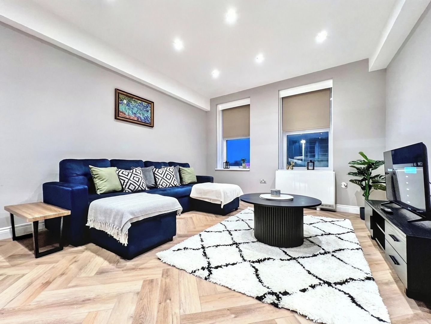 A modern living room with a blue sofa, a round coffee table, and a white rug.
