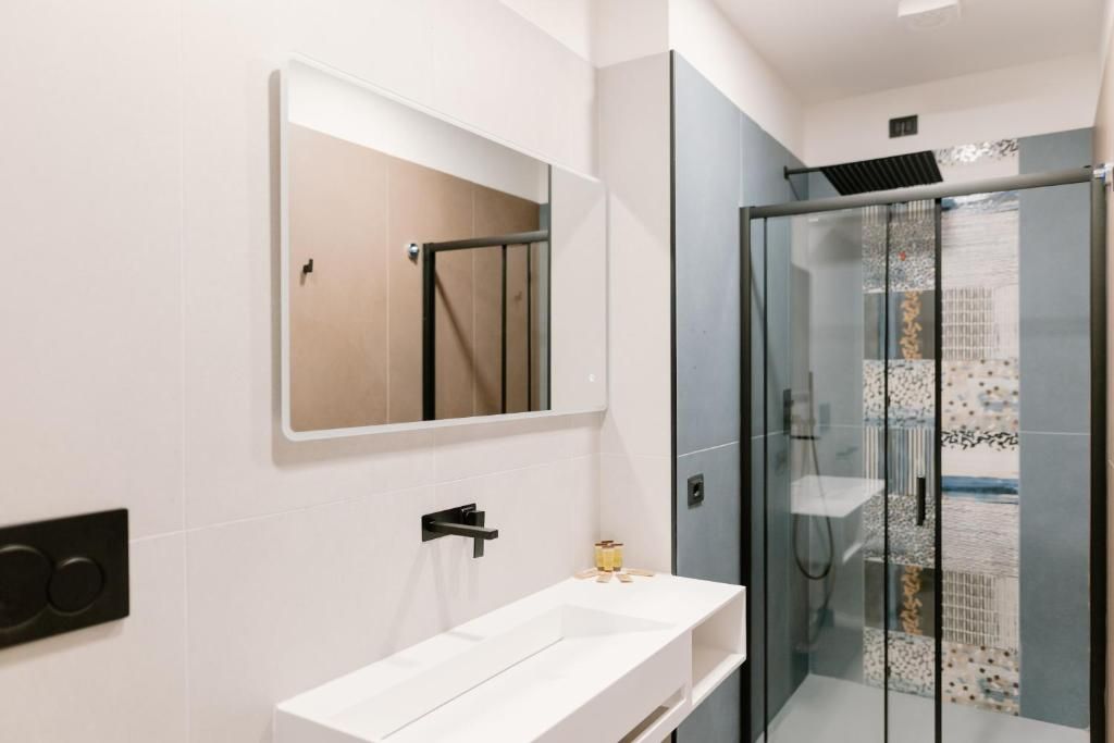 A modern bathroom with a white sink, a mirror, and a glass-enclosed shower.